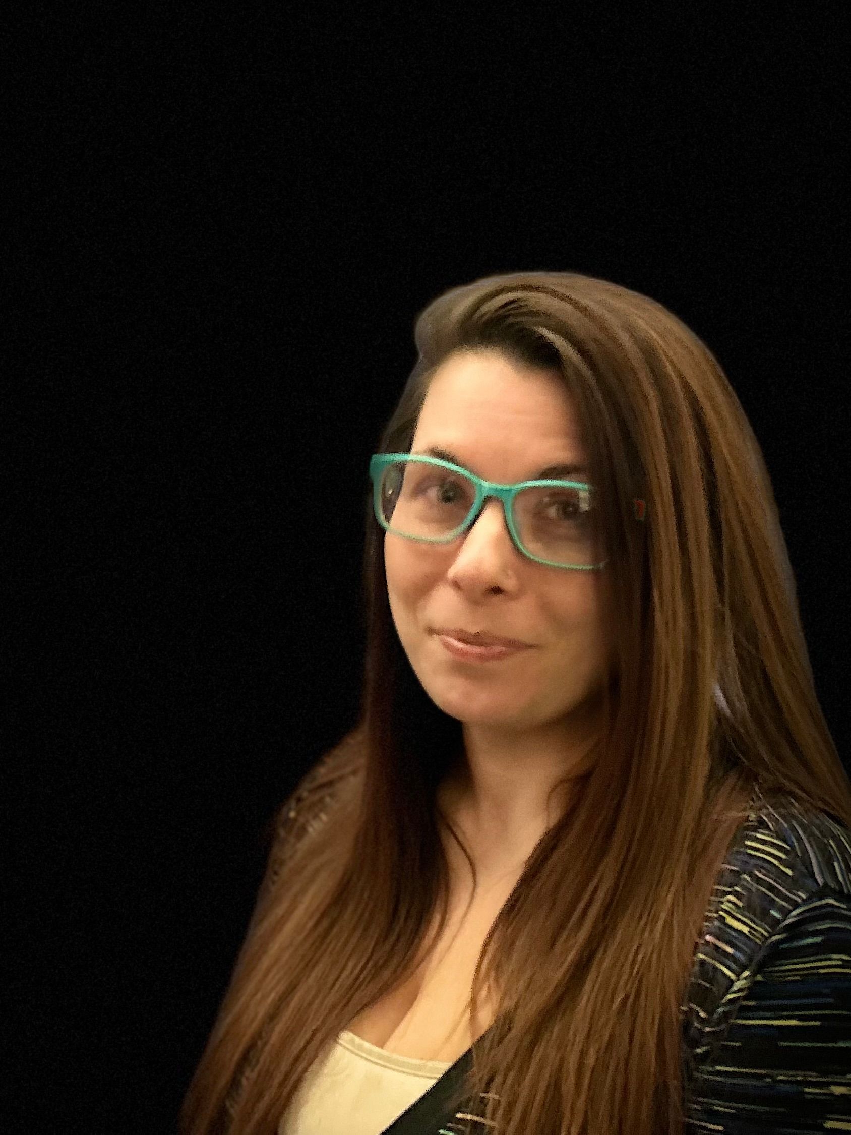 A woman with long hair and glasses is smiling for the camera.