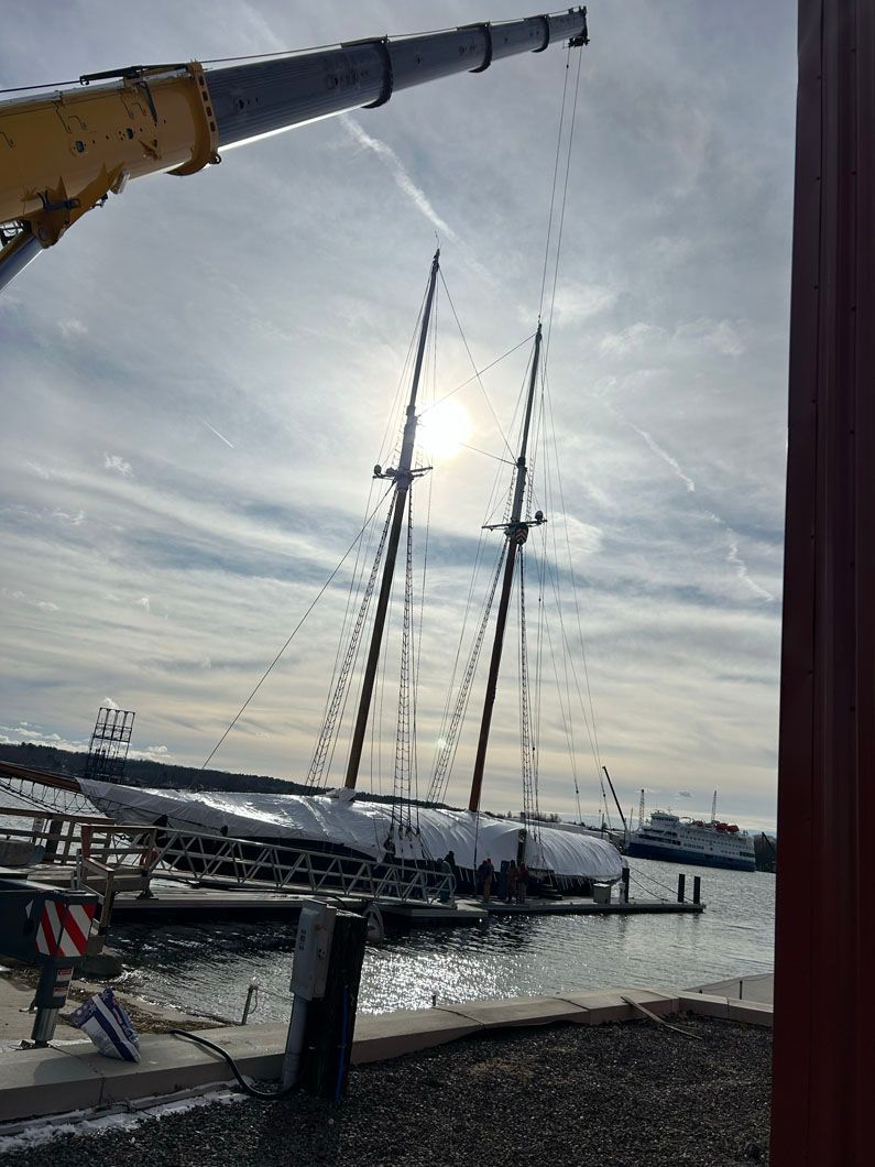 A crane is lifting a boat into the water