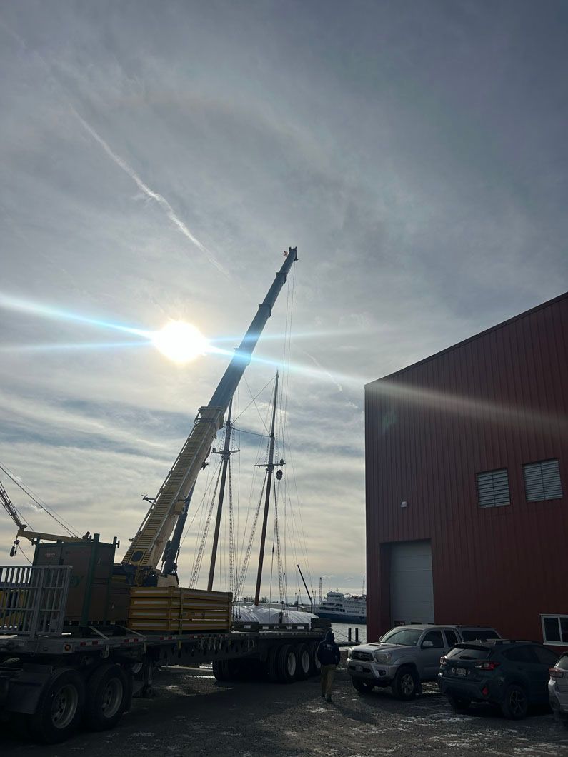 A truck with a crane on it is parked in front of a building.