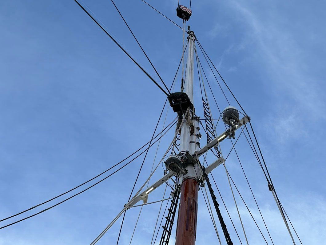 A large sailboat mast with a blue sky in the background