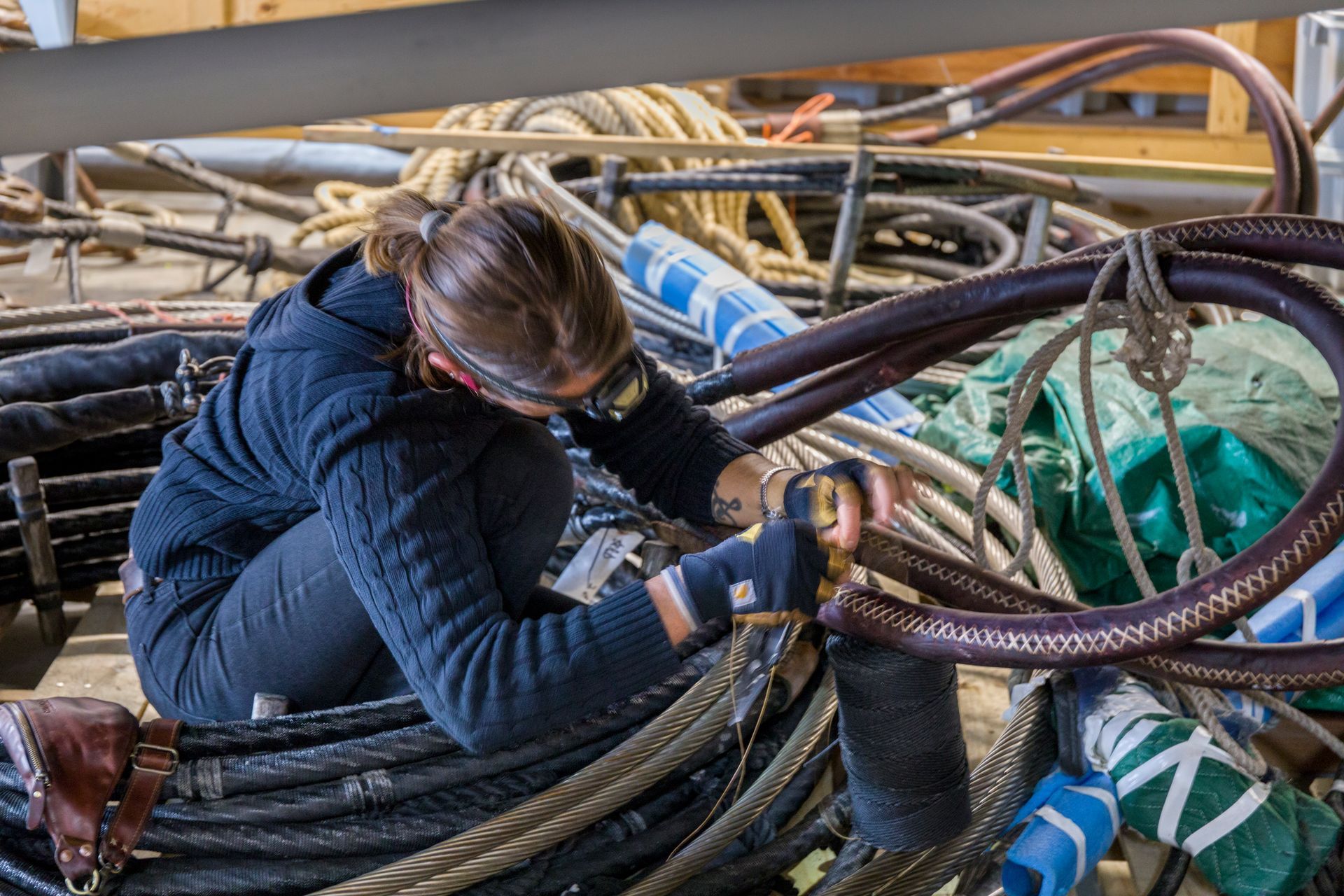 A woman is kneeling down and working on a bunch of wires.