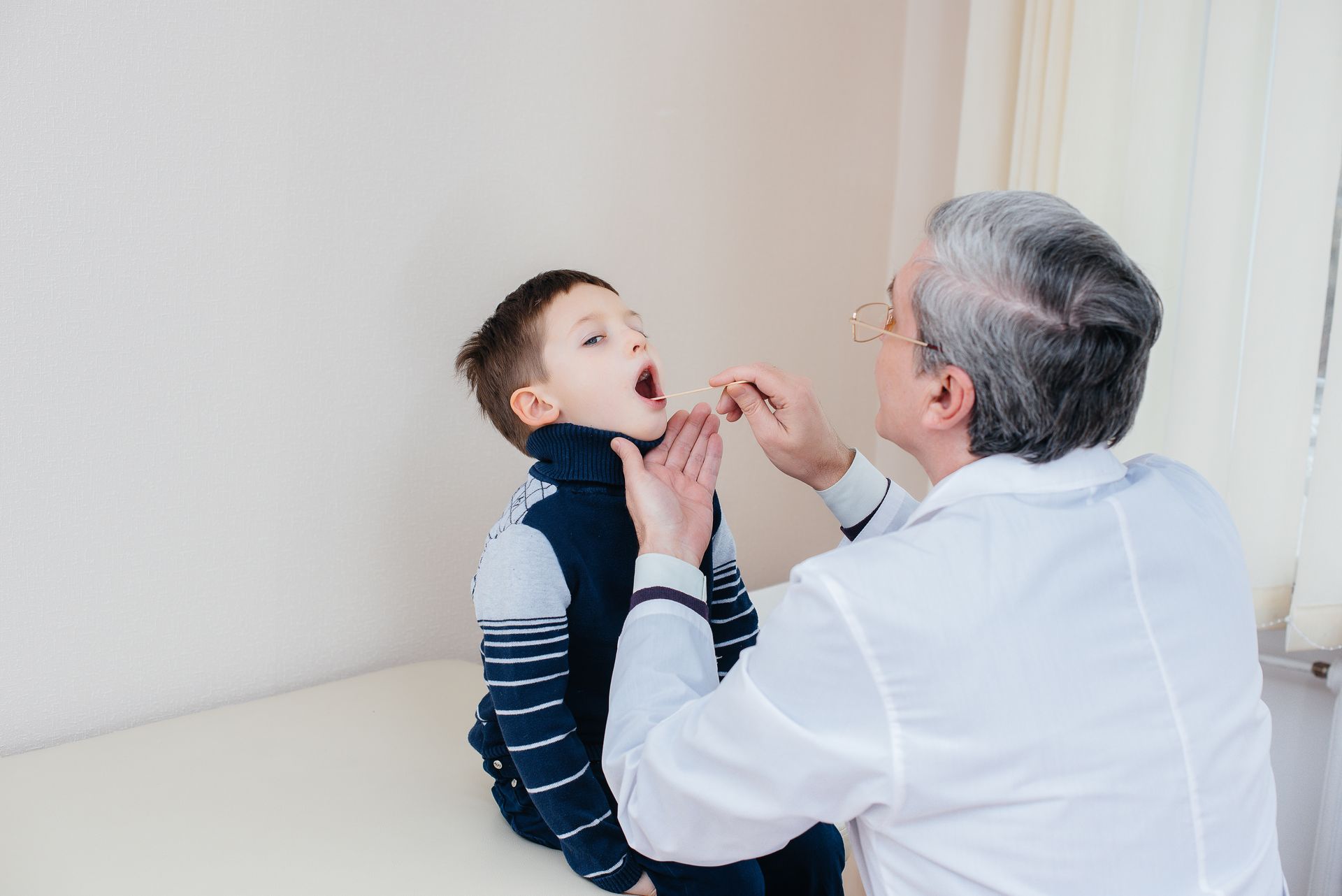 A doctor administering a diagnosis for proper strep throat treatment for kids in a clinic.