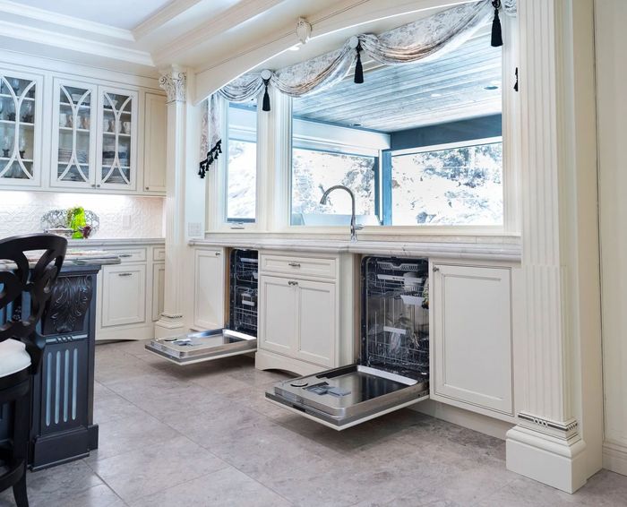 Kitchen with open dishwashers, overlooking a scenic outdoor view through a large window.