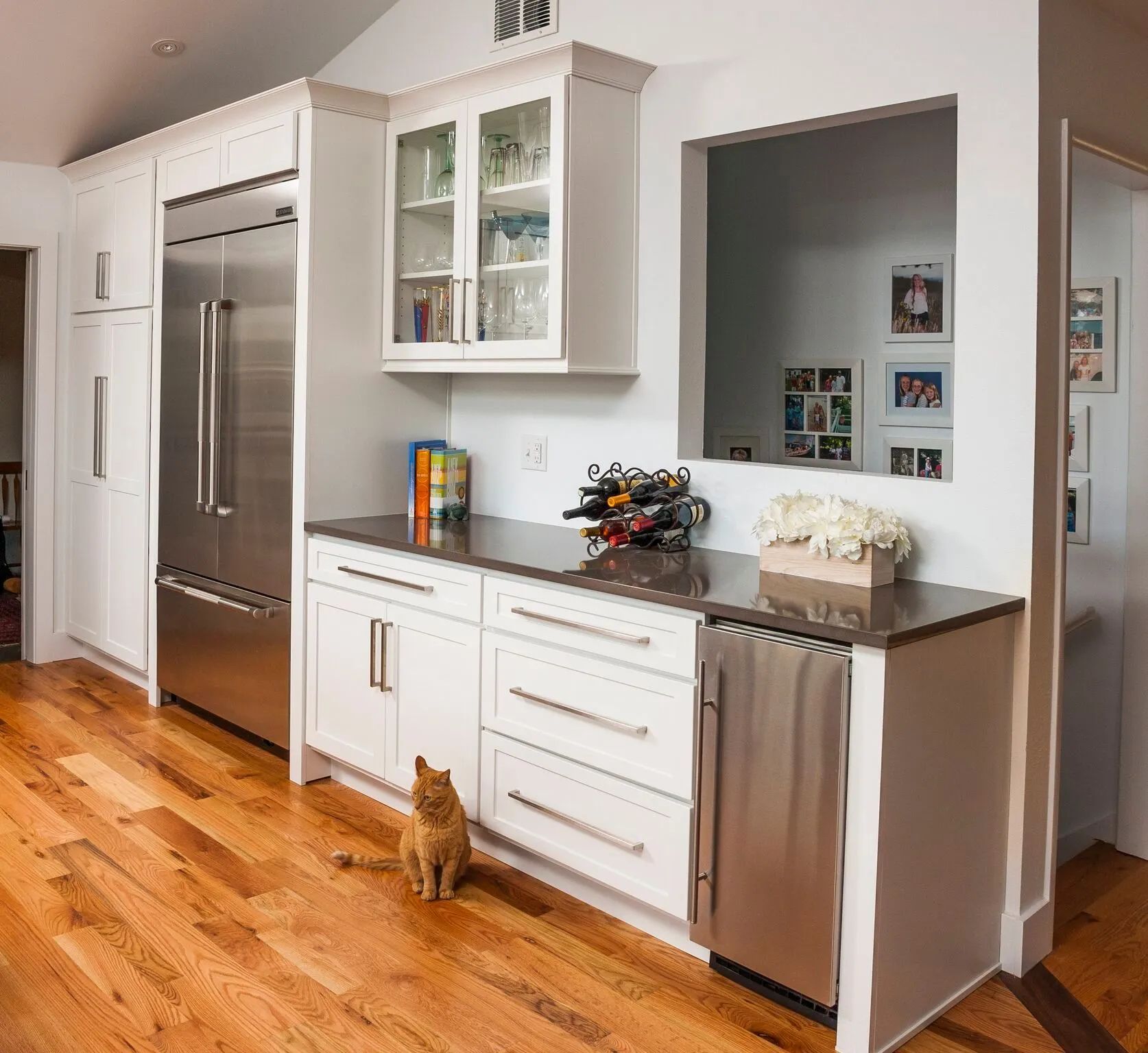 Kitchen with white cabinets, stainless steel appliances, a counter, and a cat.