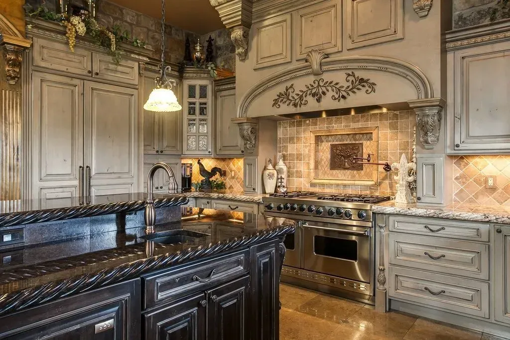 Elegant kitchen with dark island, stainless steel appliances, and ornate, light-colored cabinets.