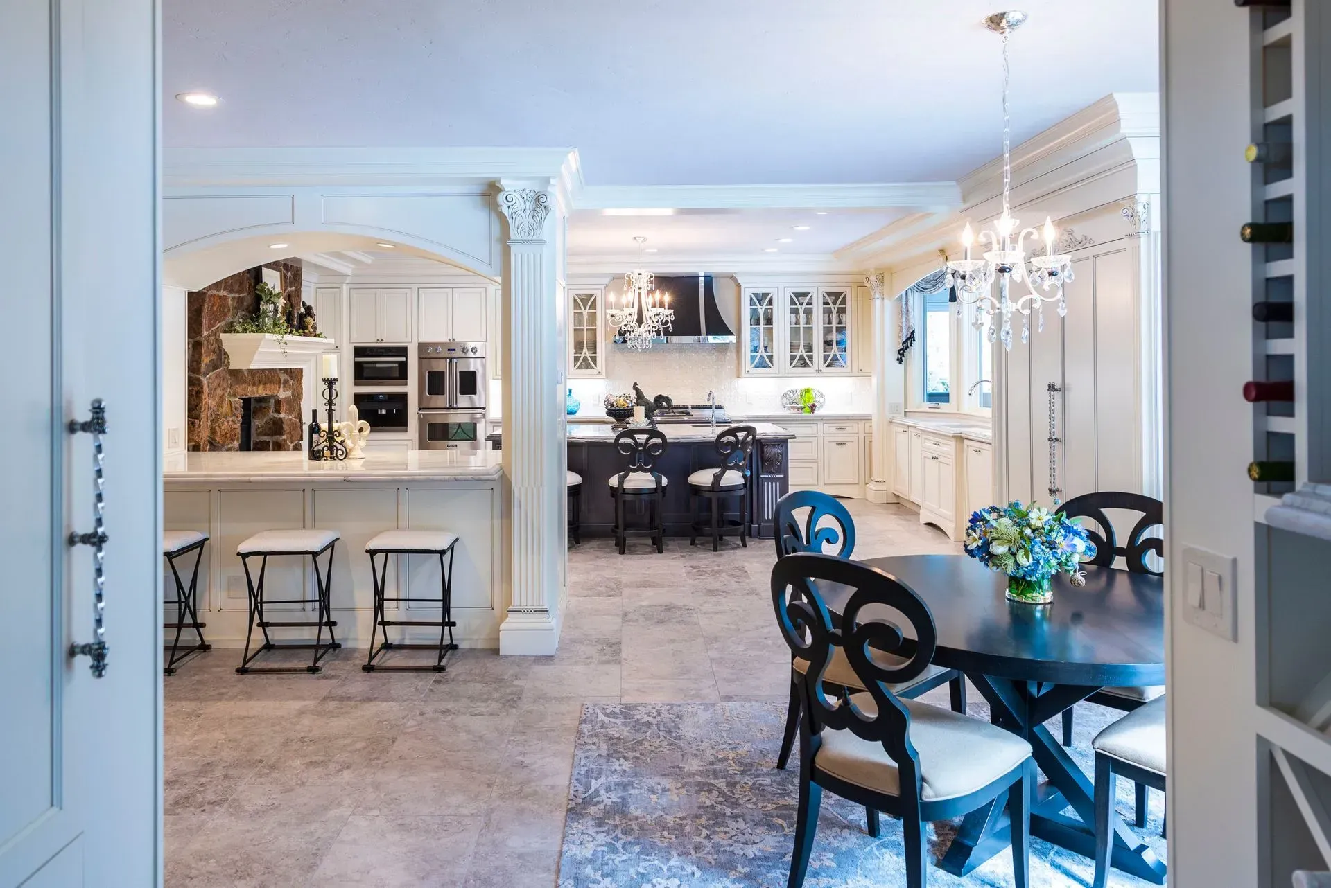 Spacious kitchen with a dining area, bar stools, and a central island; dark wood and white cabinetry.