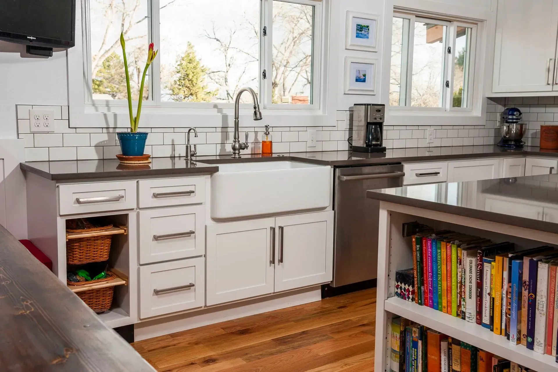 Bright white kitchen with farmhouse sink, stainless steel appliances, and cookbook shelf.