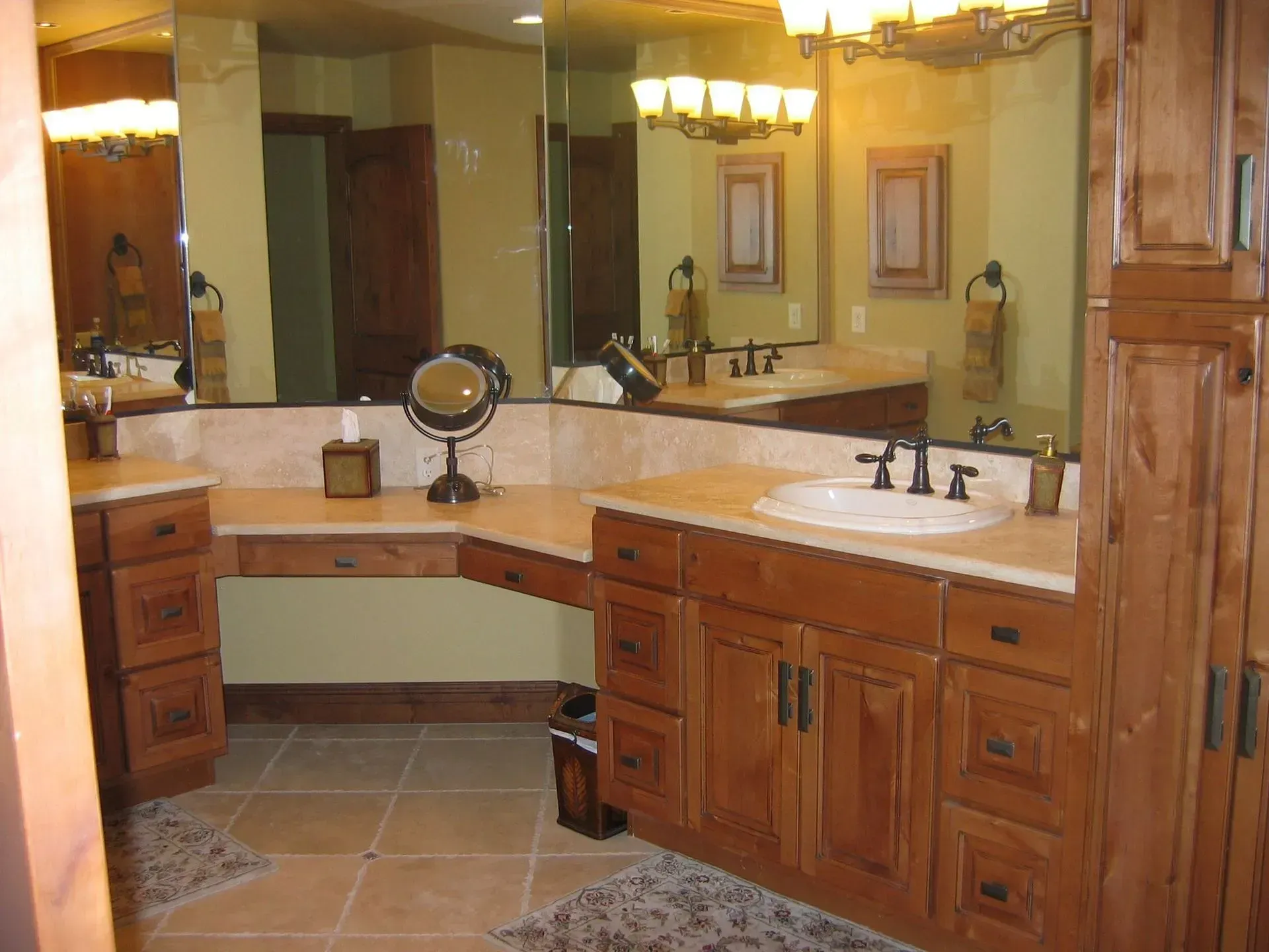 Bathroom with wood cabinetry, beige countertops, large mirror, and tile floor.
