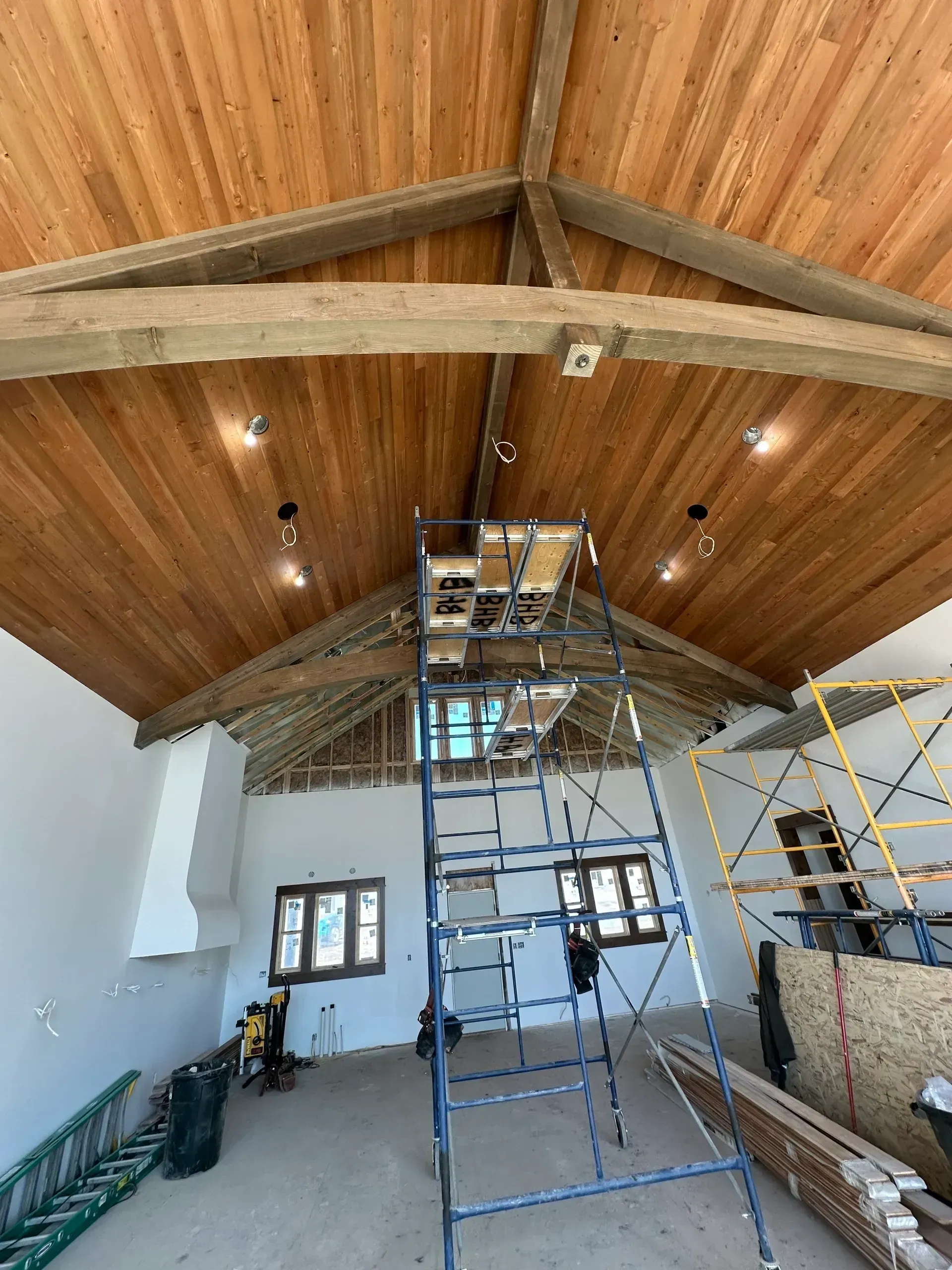 Interior view of a room under construction with a wooden ceiling, beams, and scaffolding.