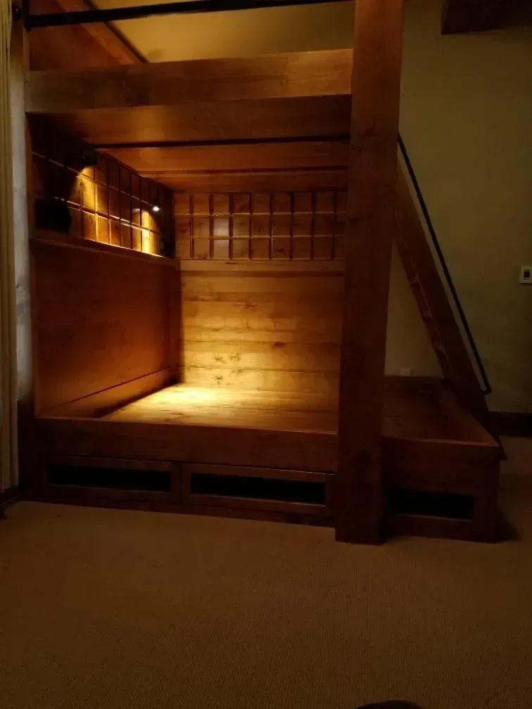 Wooden bunk bed with built-in storage and lighting.