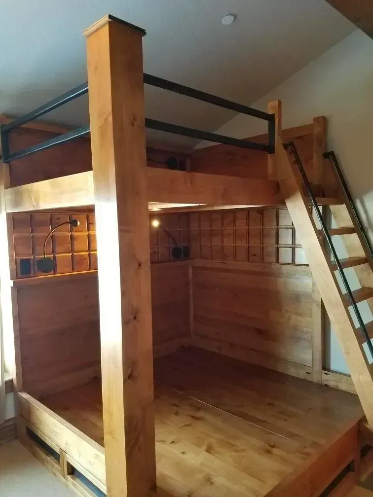 Wooden bunk beds with black metal railing and ladder.
