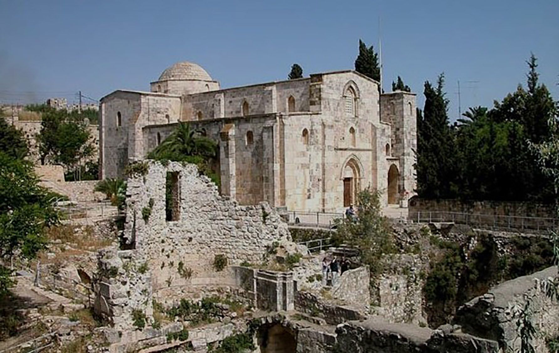 A large stone building with a dome on top of it is surrounded by trees.