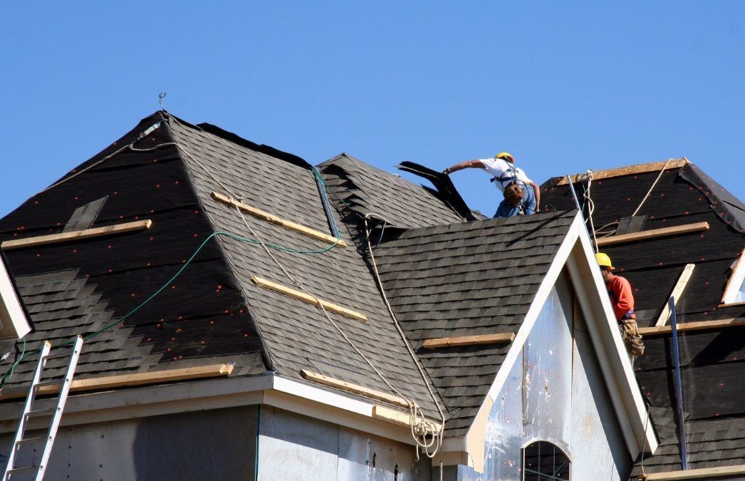 Two men are working on the roof of a house.