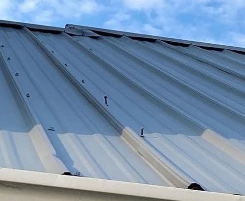 A close up of a metal roof with a blue sky in the background.