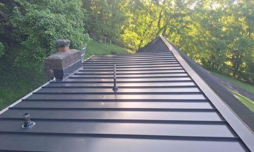 A black metal roof with a chimney on top of it.