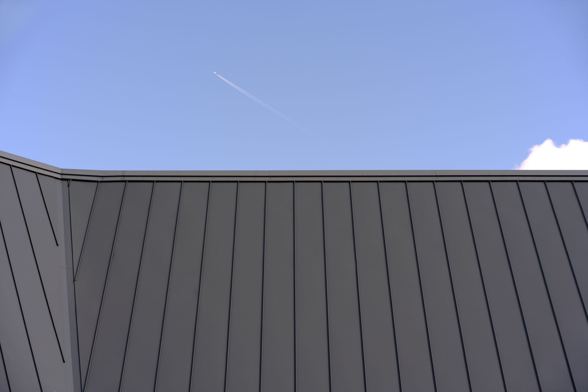 A plane is flying over a building with a blue sky in the background.