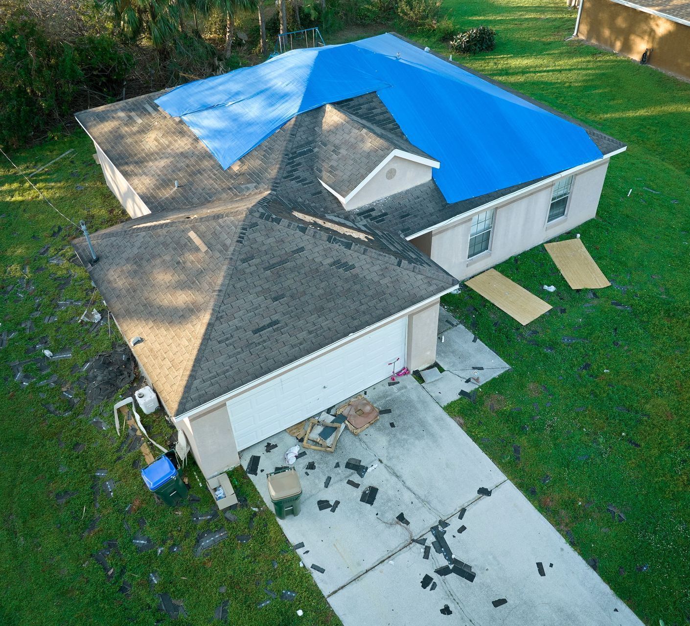 An aerial view of a house with a blue tarp on the roof