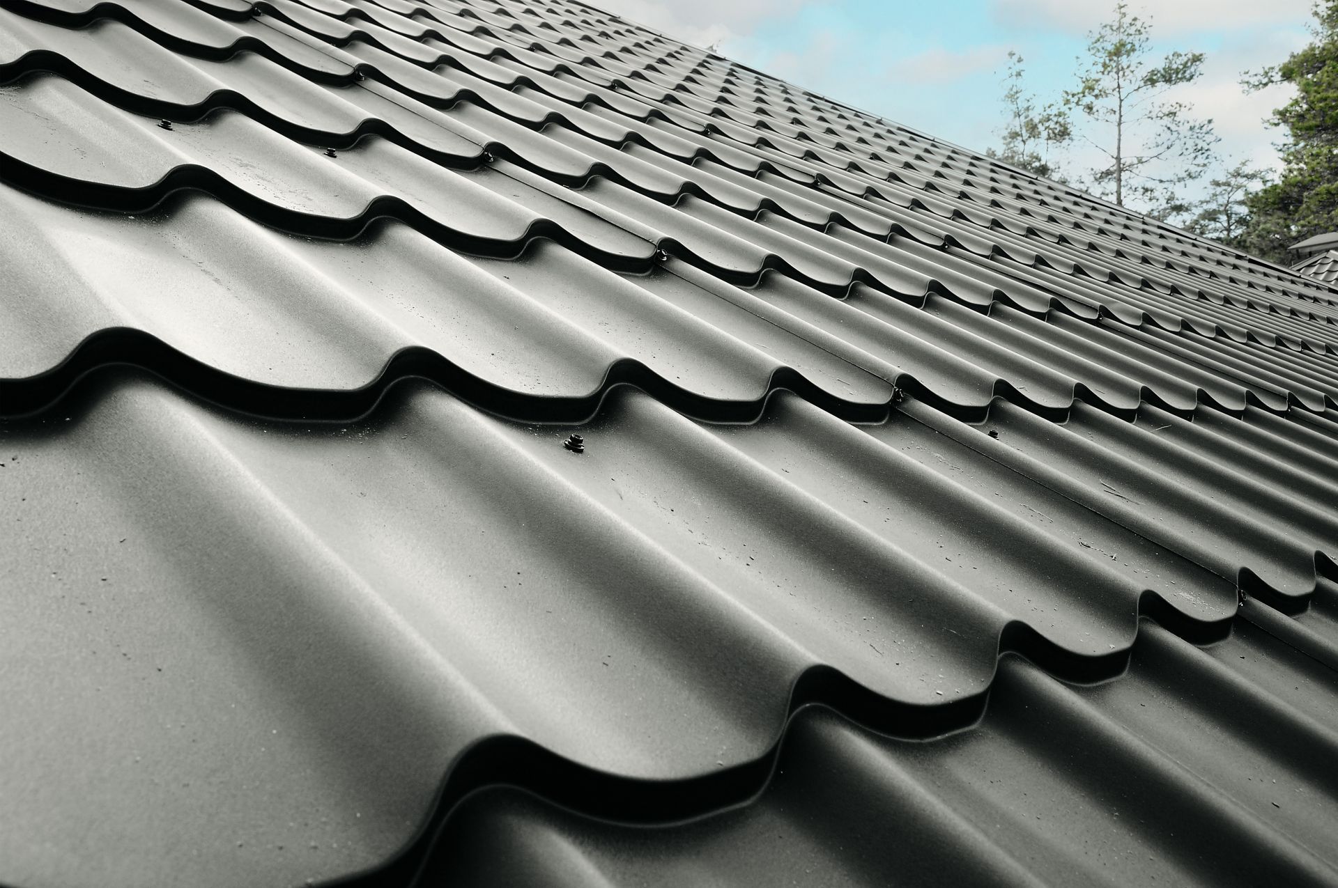 A close up of a black roof with a blue sky in the background