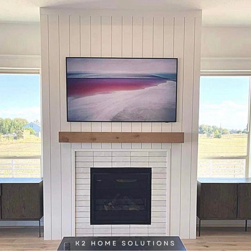 Living room with fireplace, white shiplap, TV above, and cabinets on either side.