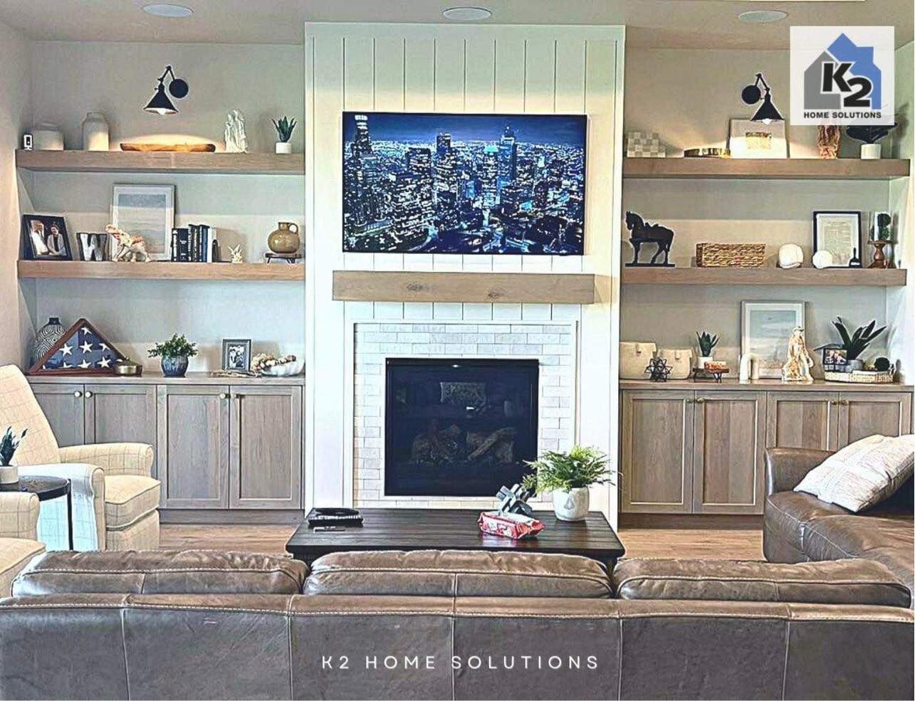 Living room with fireplace, built-ins, TV, and brown sectional sofa. Light wood shelving and cabinets.