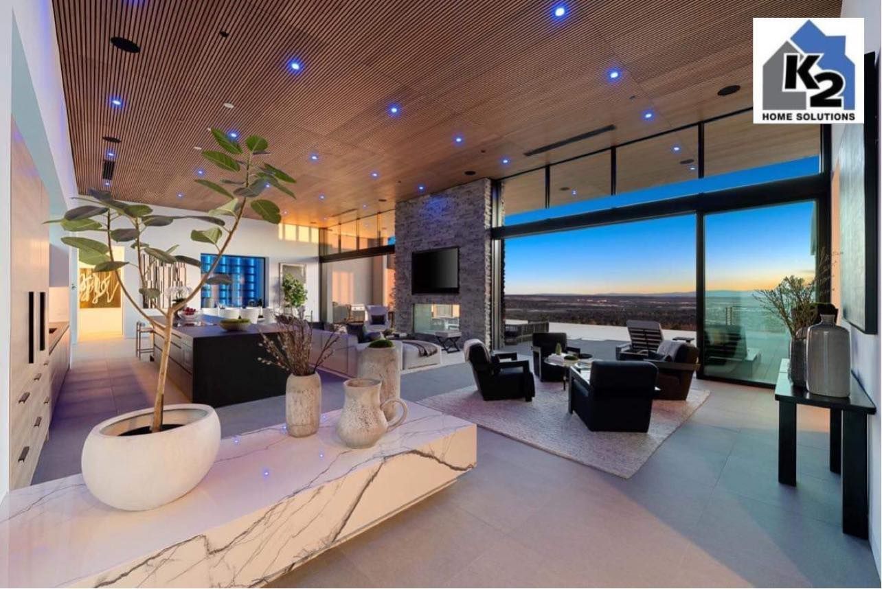 Modern luxury living room with large windows, fireplace, and scenic view.
