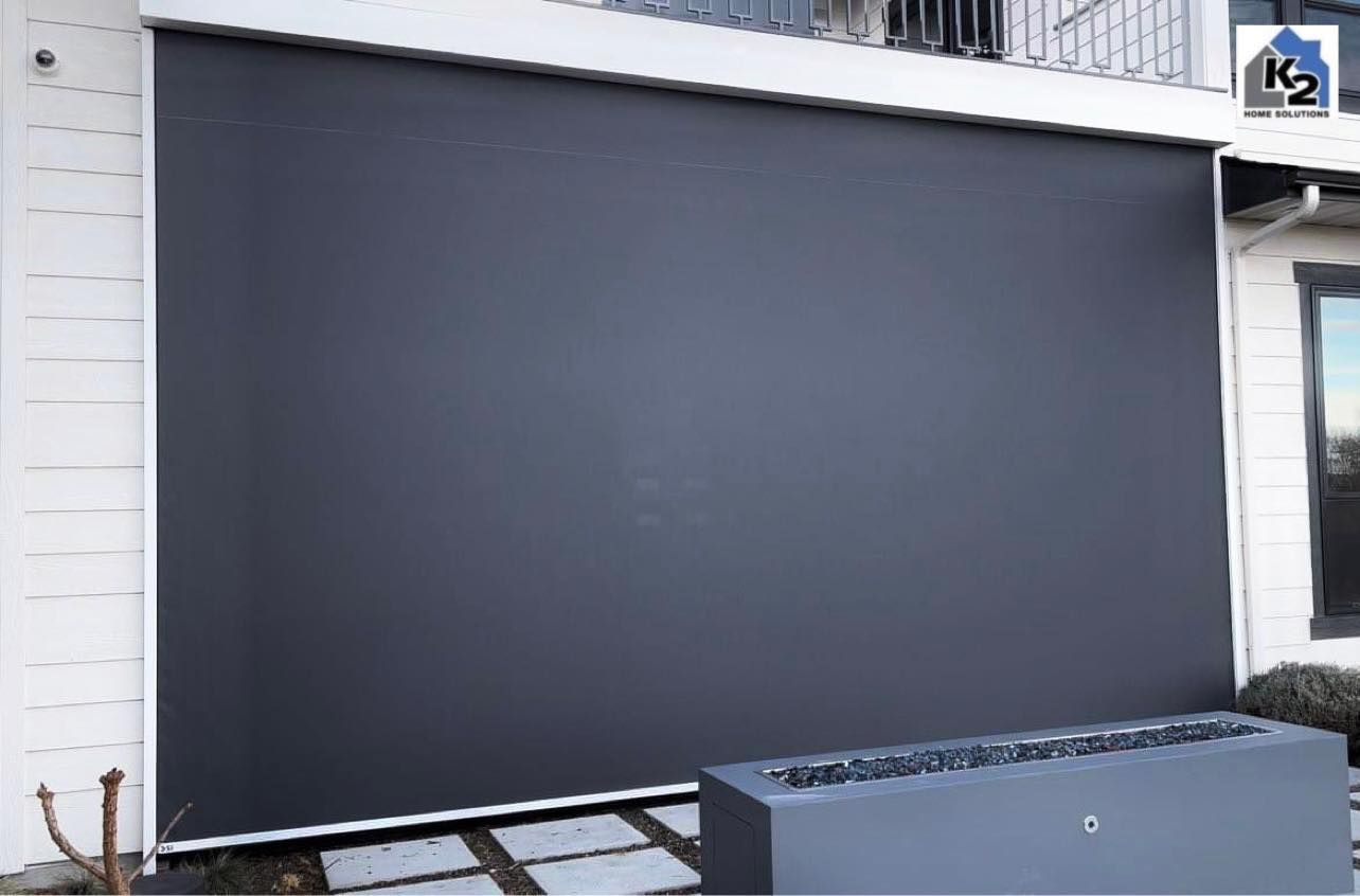 Large dark grey outdoor shade covers a white building facade.