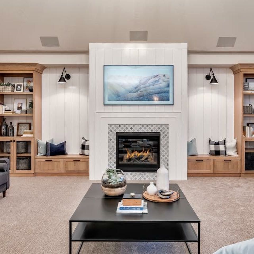Living room with fireplace, built-in shelves, TV, black coffee table, neutral carpet.
