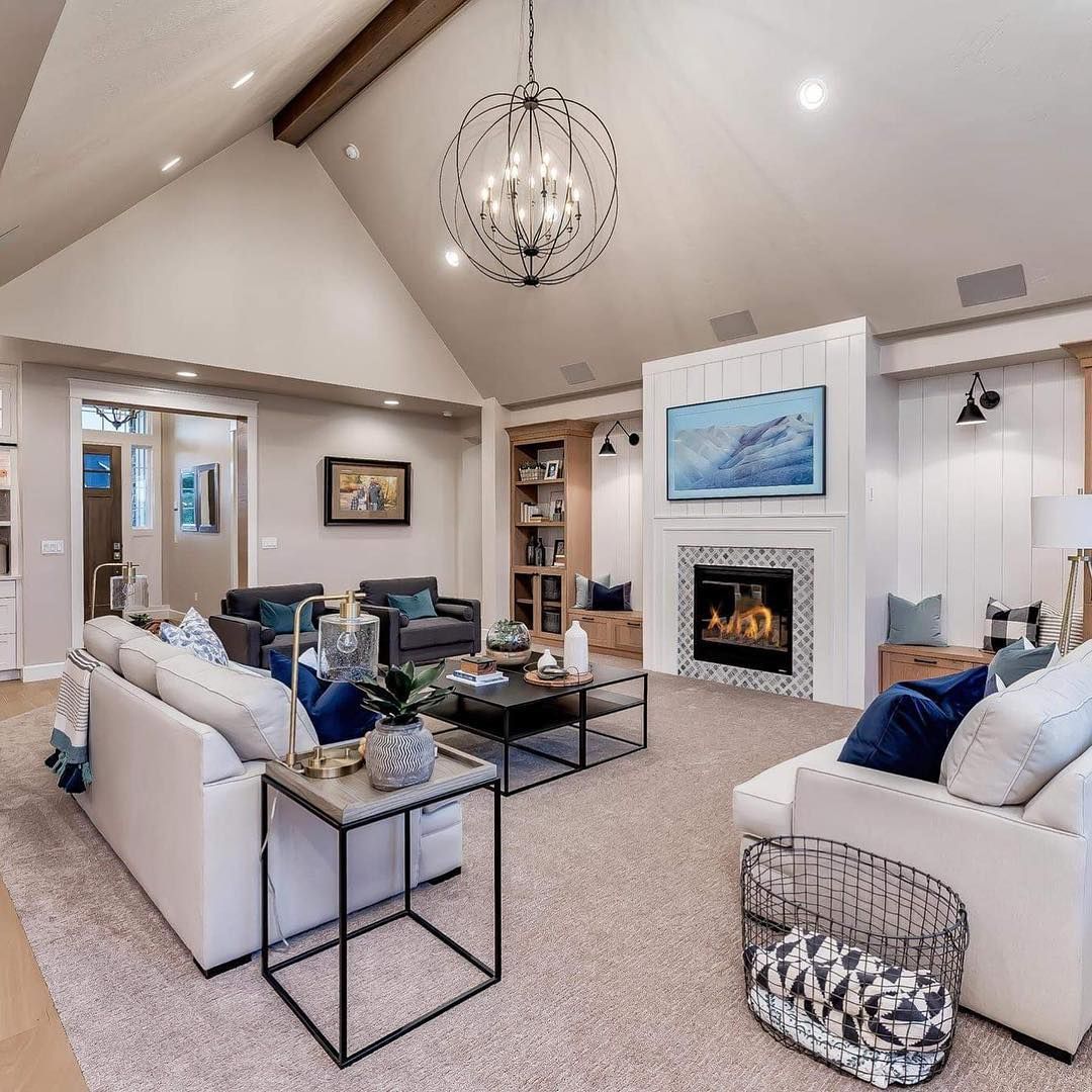 Spacious living room with vaulted ceiling, fireplace, two sofas, and contemporary lighting.
