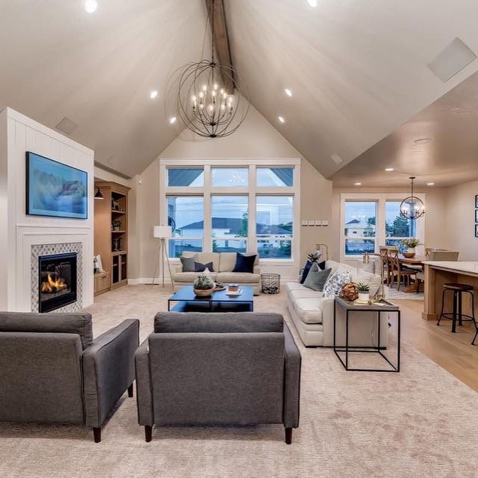 Living room with vaulted ceiling, fireplace, and two grey armchairs facing the camera.