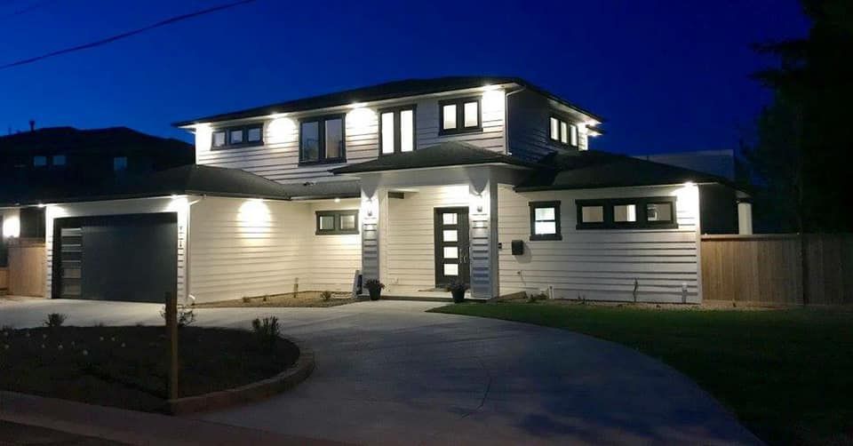 Modern white house with dark trim and lighting at dusk.