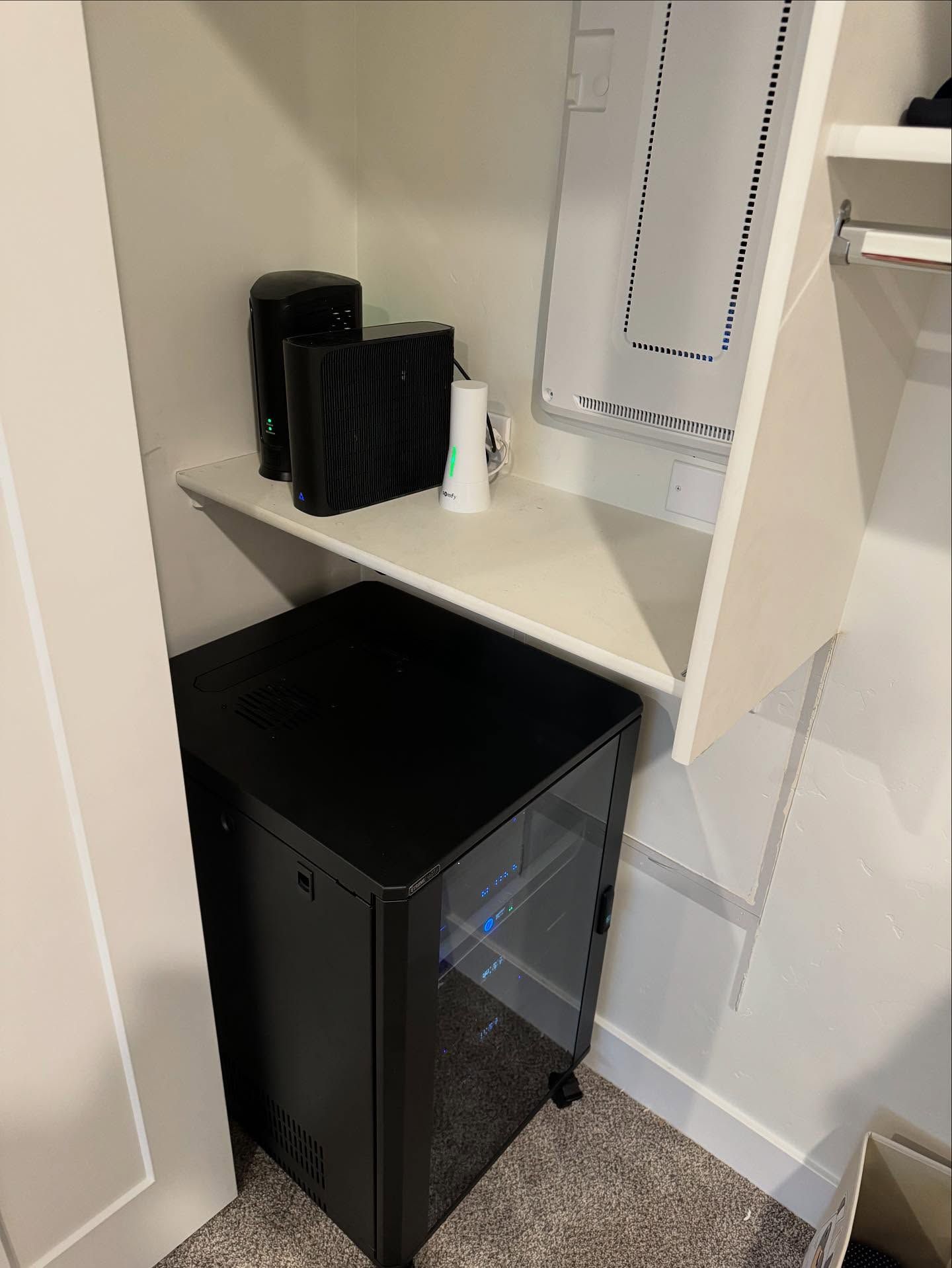A network rack and shelf with networking equipment inside a white closet.