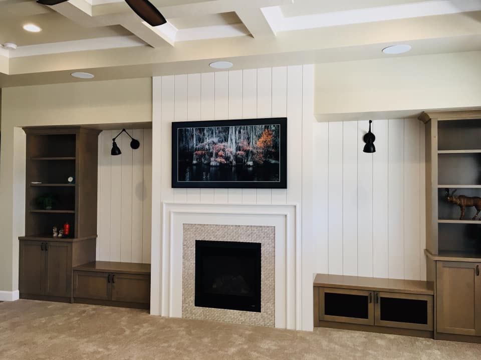 Living room with fireplace, built-in shelves, TV, and cream-colored walls. Beadboard accents.