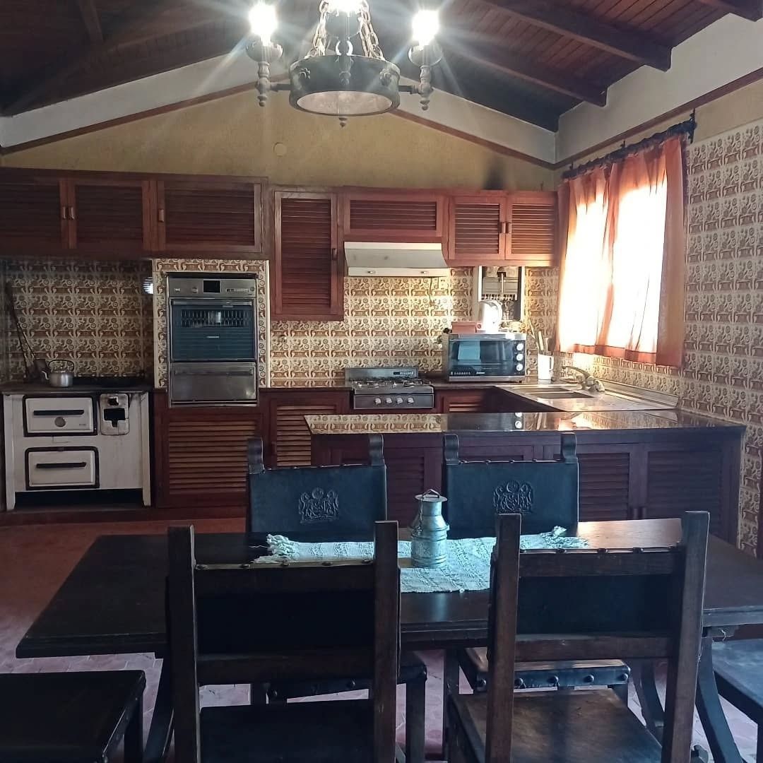 Cocina rústica con gabinetes de madera oscura y mesa de comedor