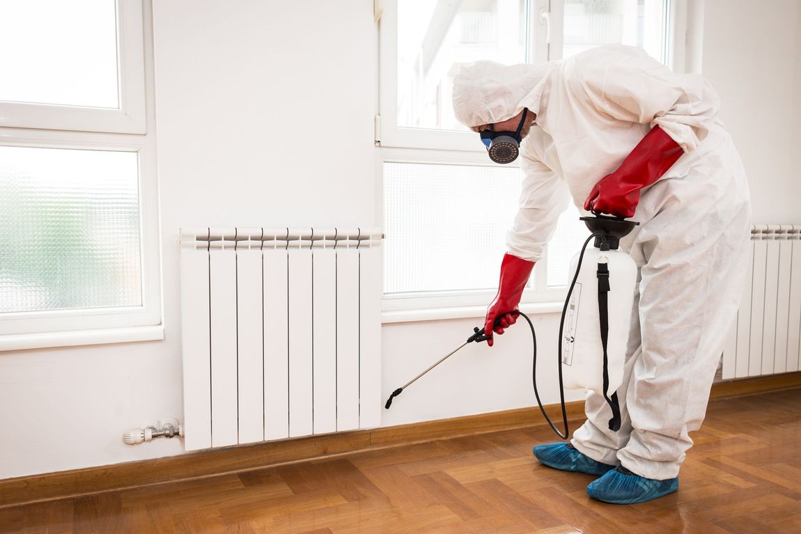 A Man in a Protective Suit is Spraying a Room With a Sprayer