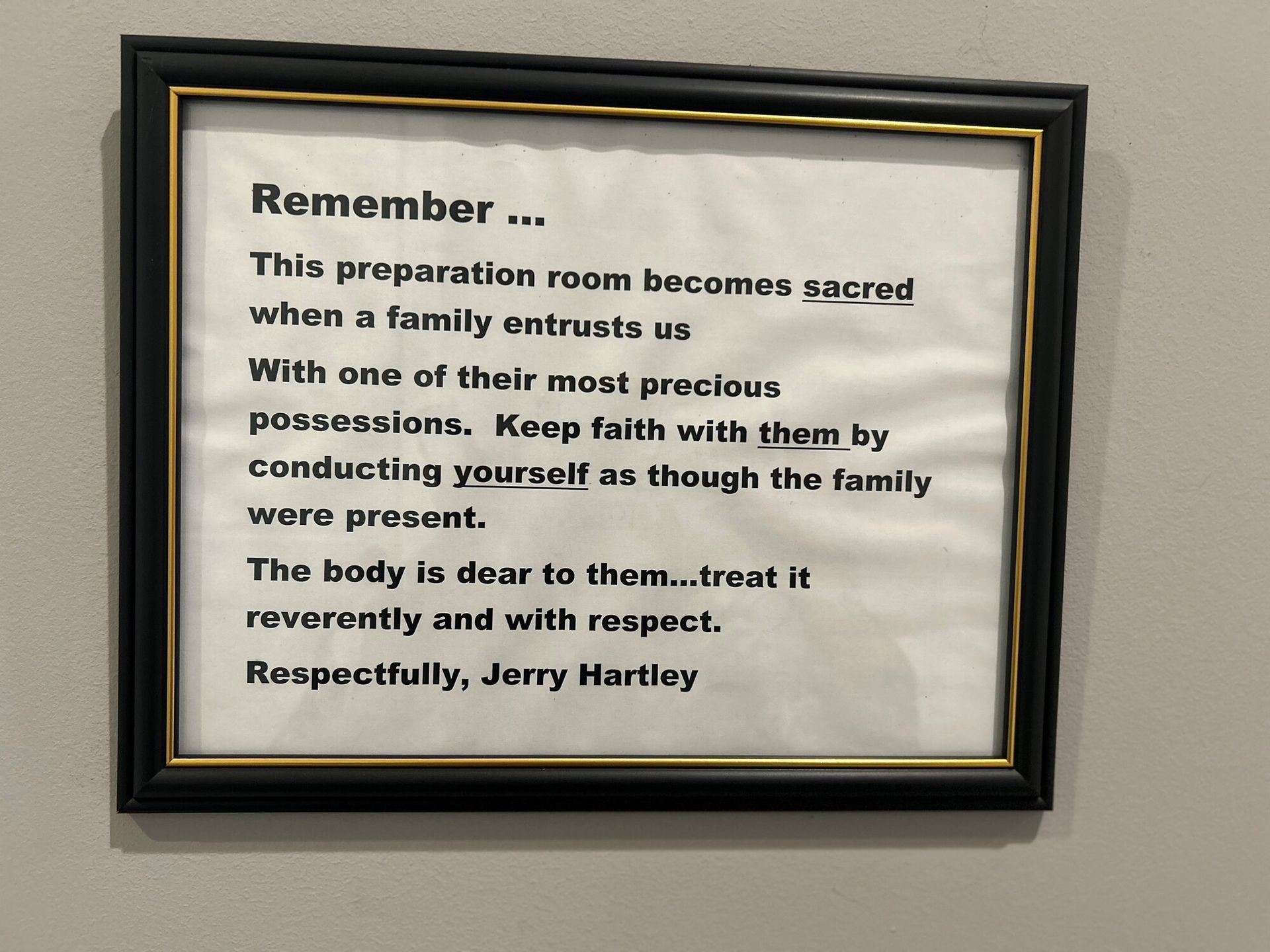Framed sign: Text about treating a body with respect in a preparation room. Signed by Jerry Hartley.