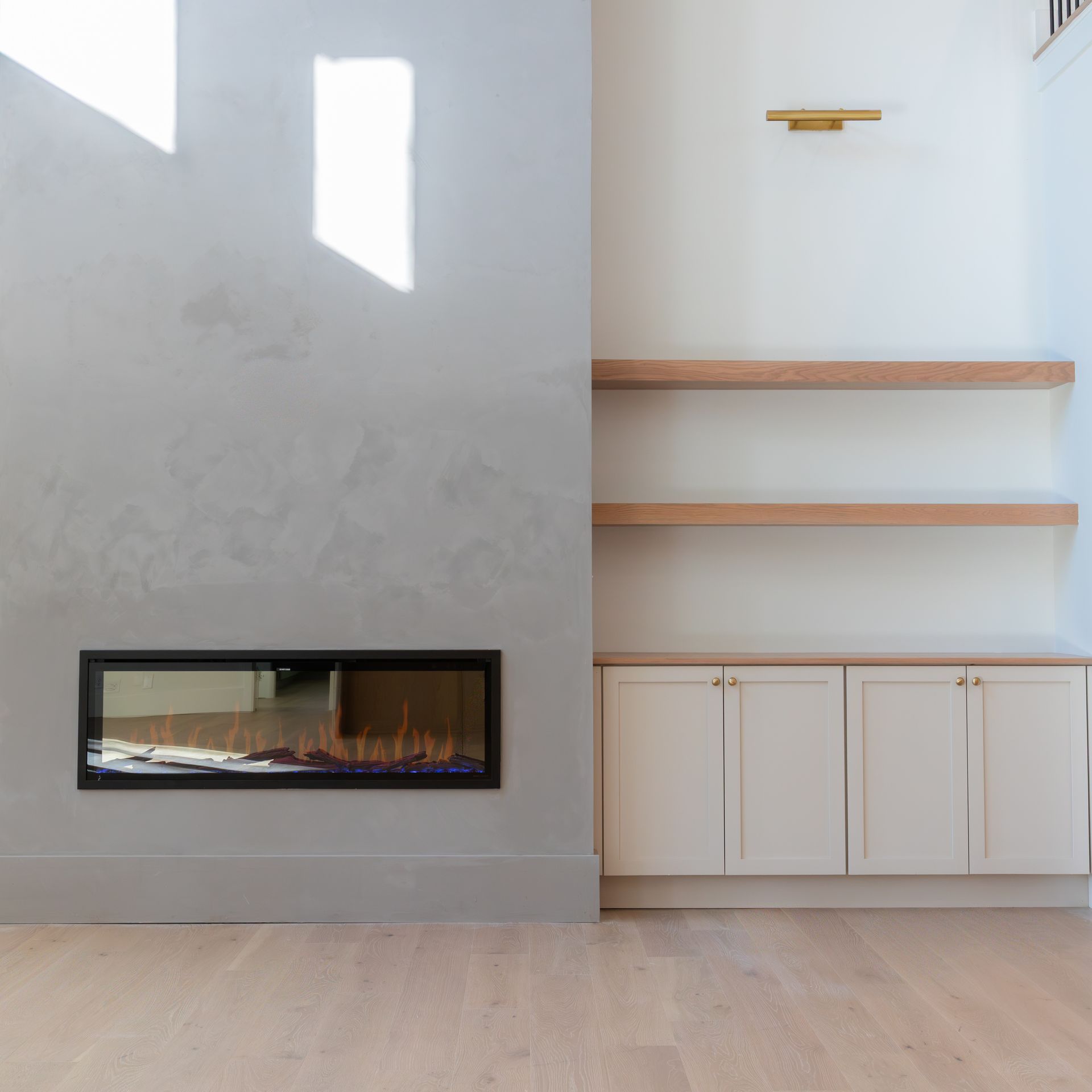 Modern living room with fireplace, built-in shelves, and white cabinets against a light gray wall.