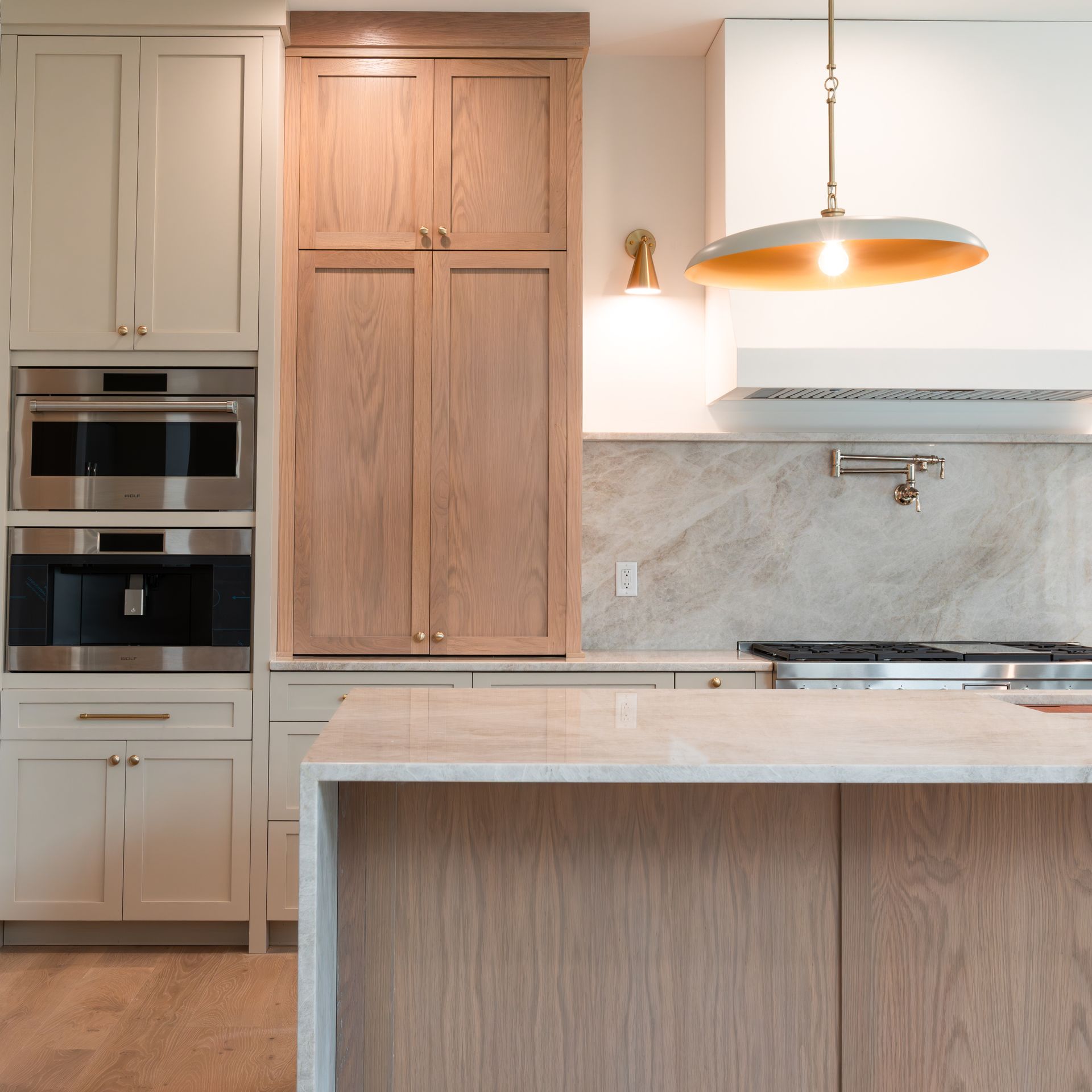 Modern kitchen with light wood cabinetry, stone countertops, and a pendant light.