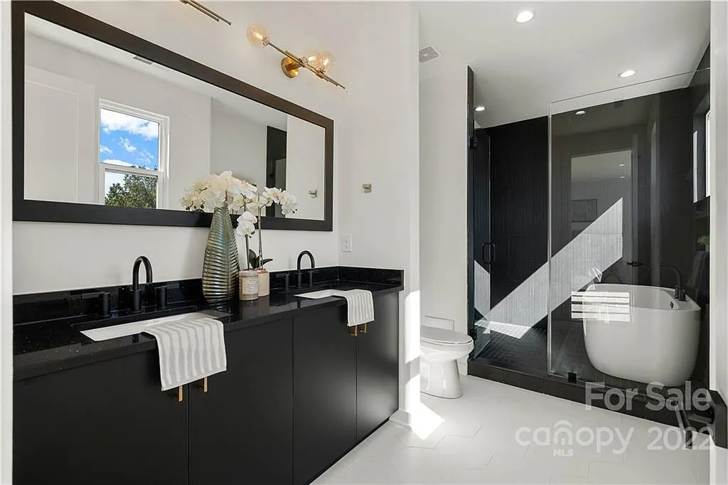 Modern bathroom with black vanity, white floors, and a glass shower.