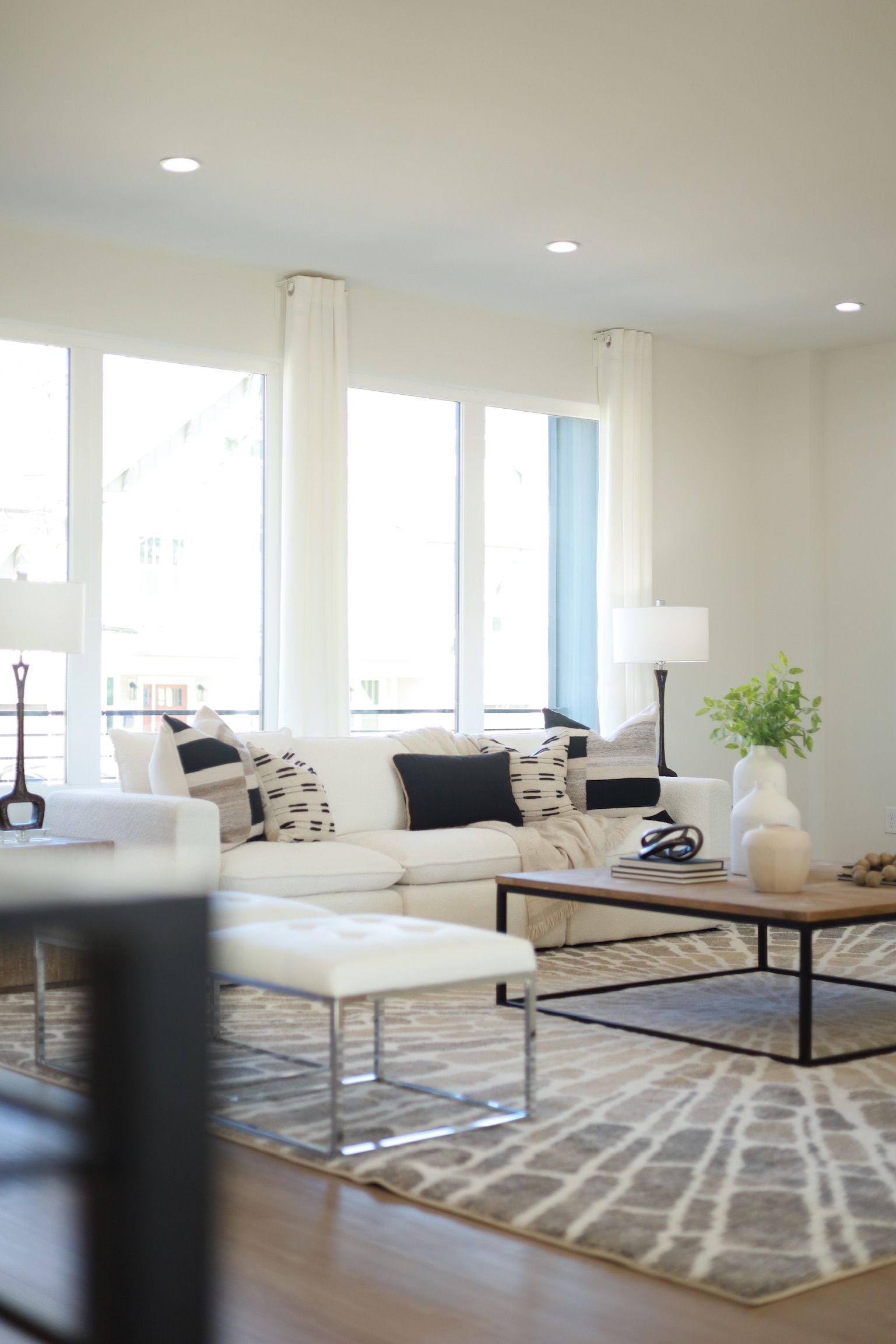 Living room with white sofa, light rug, and large windows.