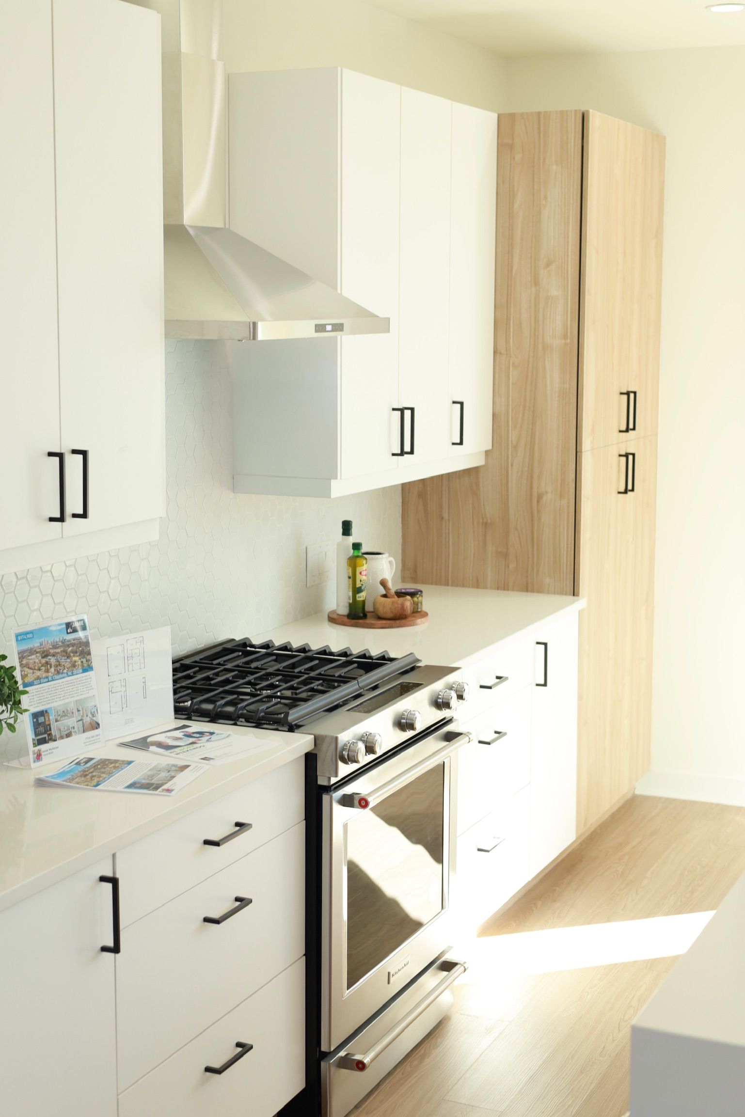 Modern kitchen with white cabinets, stainless steel appliances, and light wood paneling.