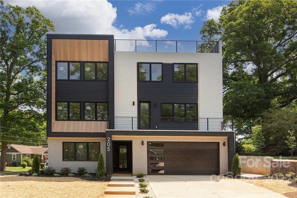 Modern three-story house with a gray facade, black accents, and wood paneling. 