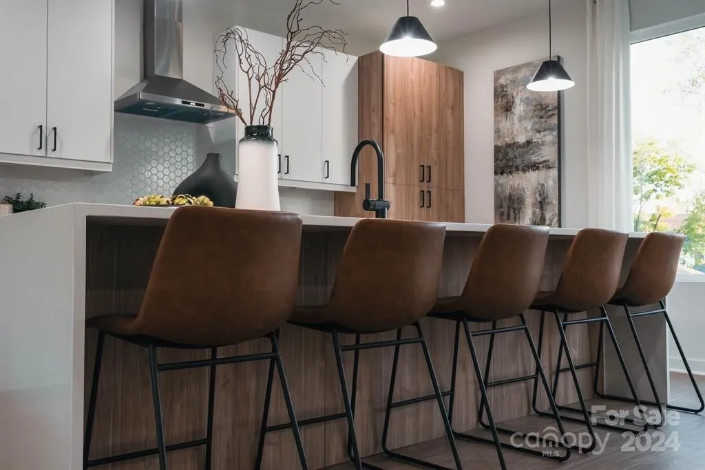 Modern kitchen with brown bar stools, wood cabinets, and black accents.