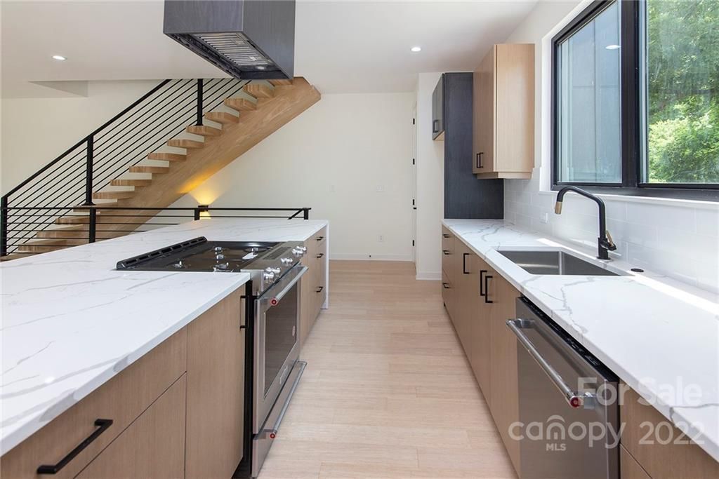 Modern kitchen with white countertops, stainless steel appliances, and light wood cabinets.