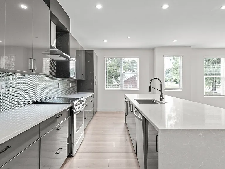 Modern gray kitchen with white countertops, stainless steel appliances, and an island with a sink.