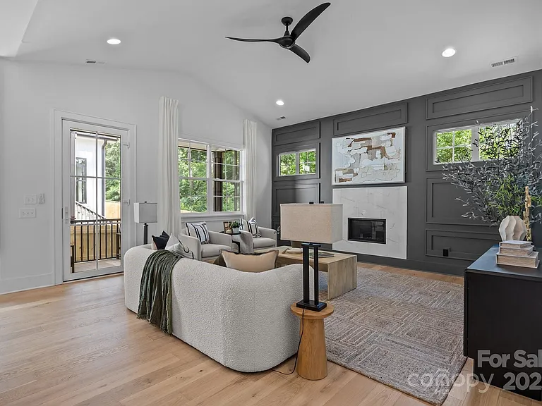 Living room with white walls, dark gray accent wall, fireplace, and light wood floors.