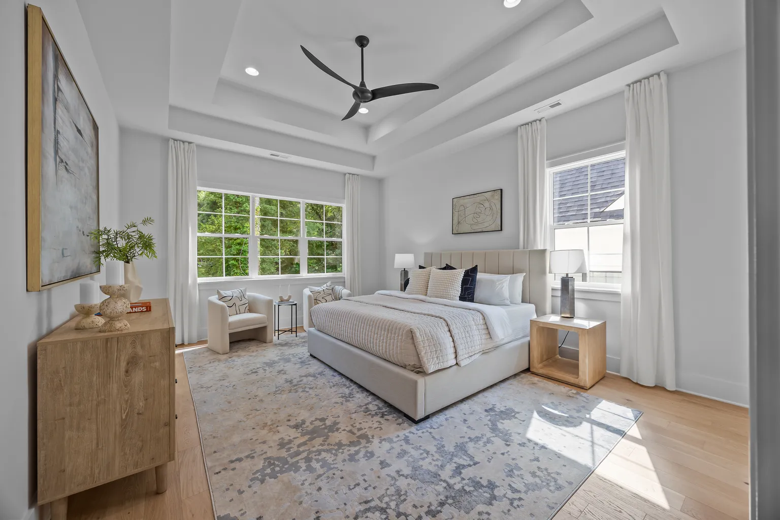 Bedroom with large windows, light-colored walls, wood floors, and a modern bed.