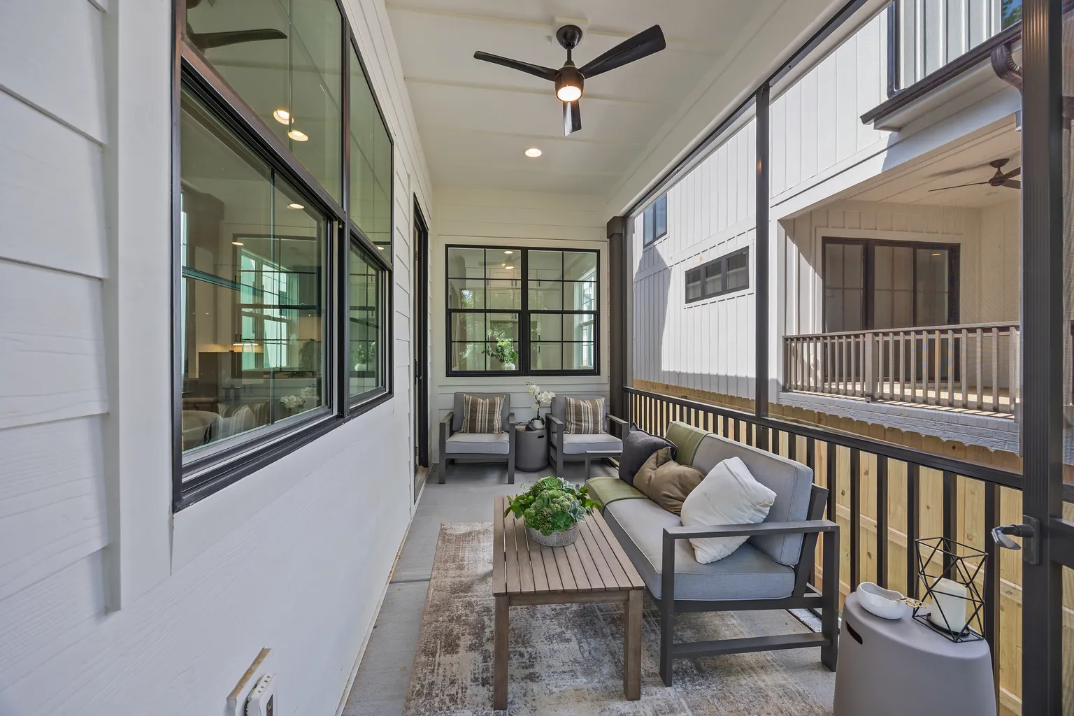 Outdoor balcony with gray furniture, coffee table, plants, and view.