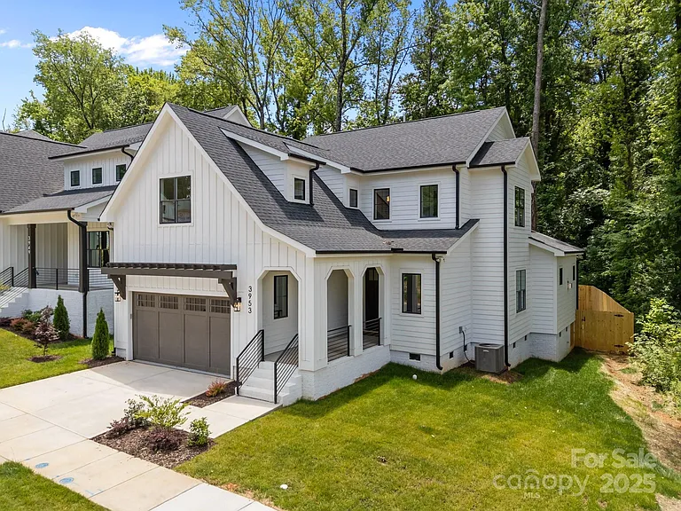 White farmhouse-style home with black roof and trim, arched entryway, and two-car garage.