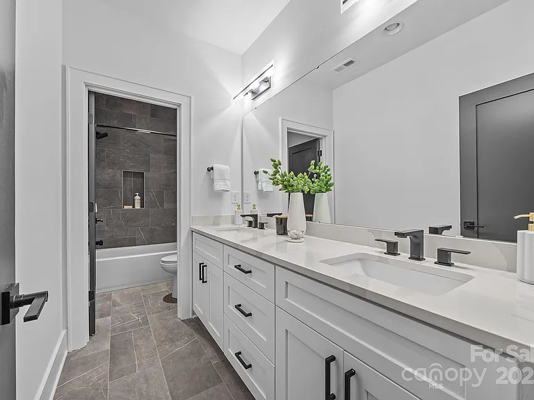 Modern bathroom with white vanity, black fixtures, and gray tile floor.