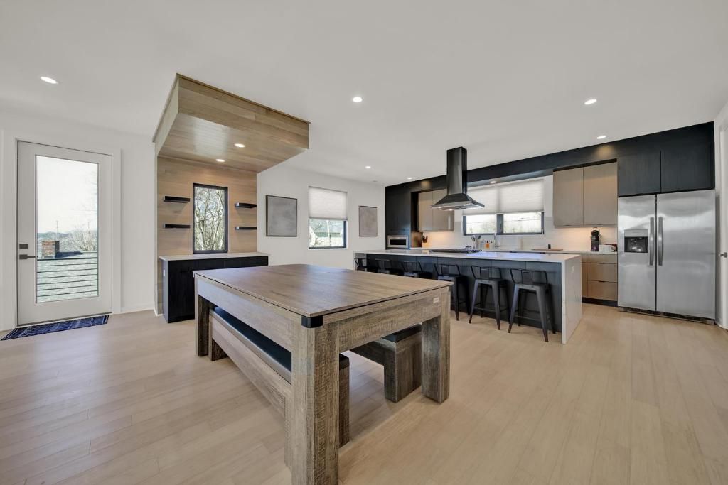 Modern kitchen and entertainment space with pool table, island with stools, and stainless steel appliances.